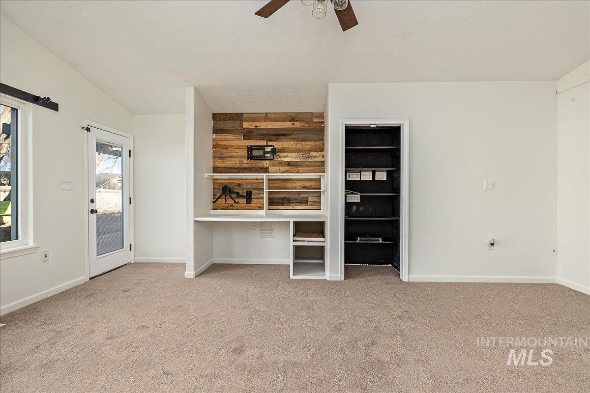 Unfurnished living room with light colored carpet and ceiling fan