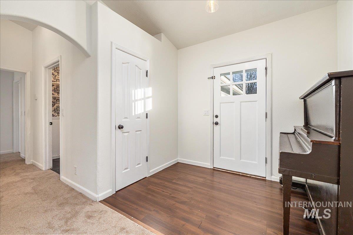 Foyer with arched walkways, dark wood-style floors, and dark colored carpet