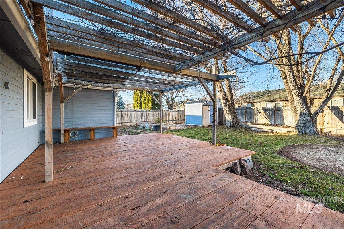 Wooden terrace featuring a storage shed and a fenced backyard