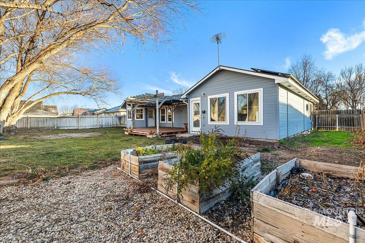 Rear view of house featuring a fenced backyard, a vegetable garden, a deck, and a pergola