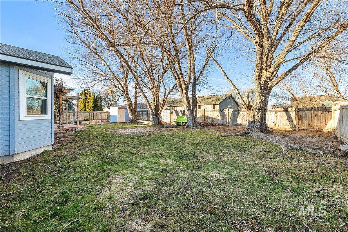 Fenced backyard featuring a storage shed