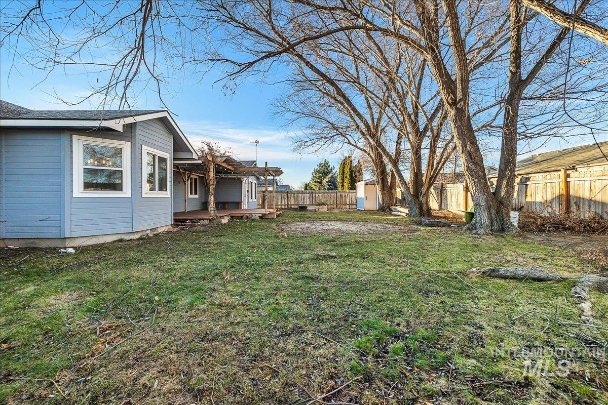 Fenced backyard featuring a shed and a wooden deck