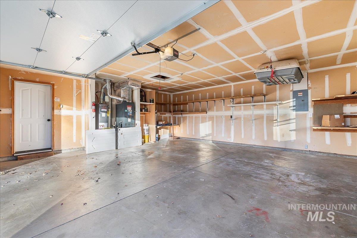 Garage with electric panel, water heater, heating unit, and a garage door opener