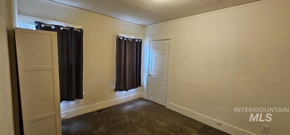 Empty room with dark colored carpet and baseboards