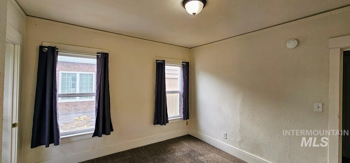 Empty room featuring baseboards and dark carpet