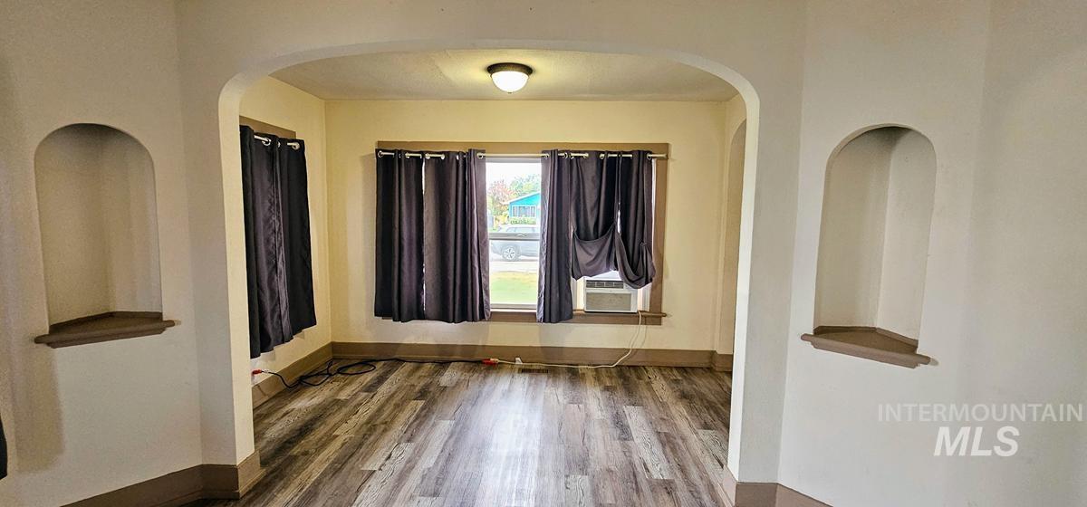 Unfurnished room featuring wood finished floors and arched walkways
