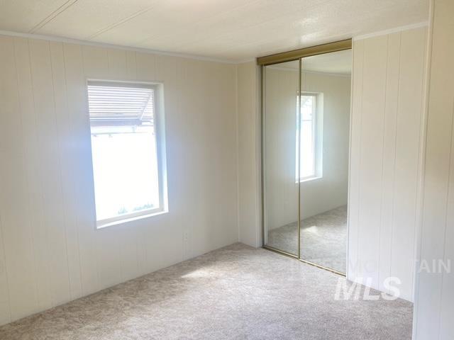 Bedroom featuring a closet, carpet, wood walls, and a decorative wall