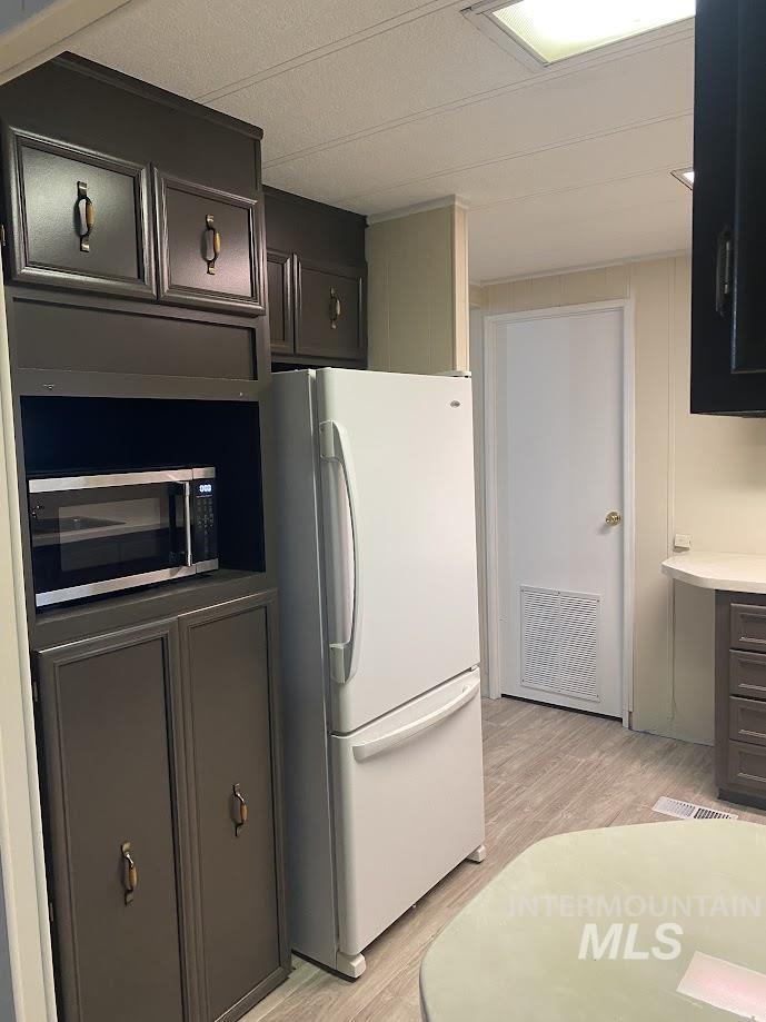 Kitchen with freestanding refrigerator, light wood-style flooring and light countertops