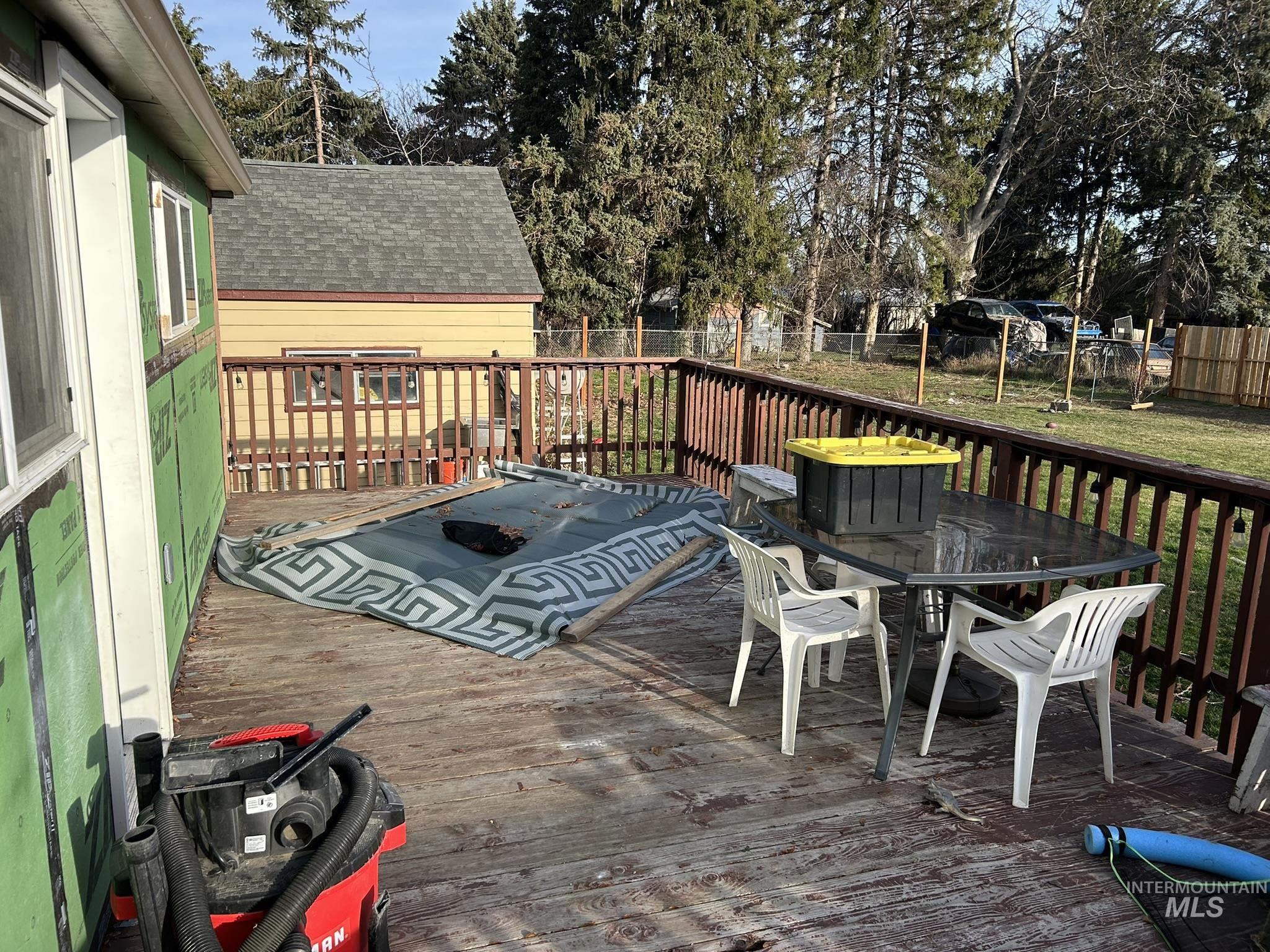 Wooden terrace with outdoor dining space and a fenced backyard