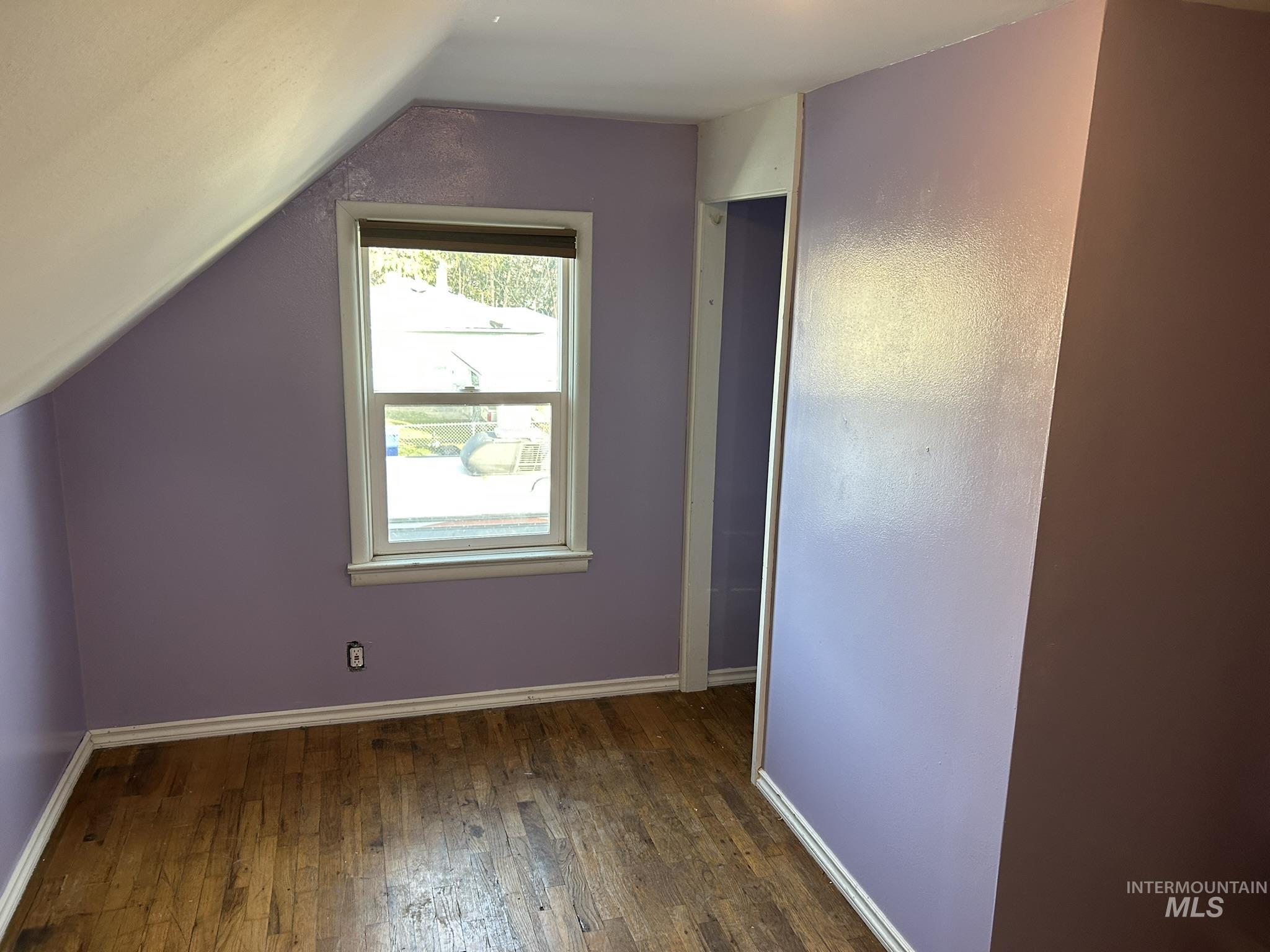 Bonus room with dark wood-style flooring and lofted ceiling