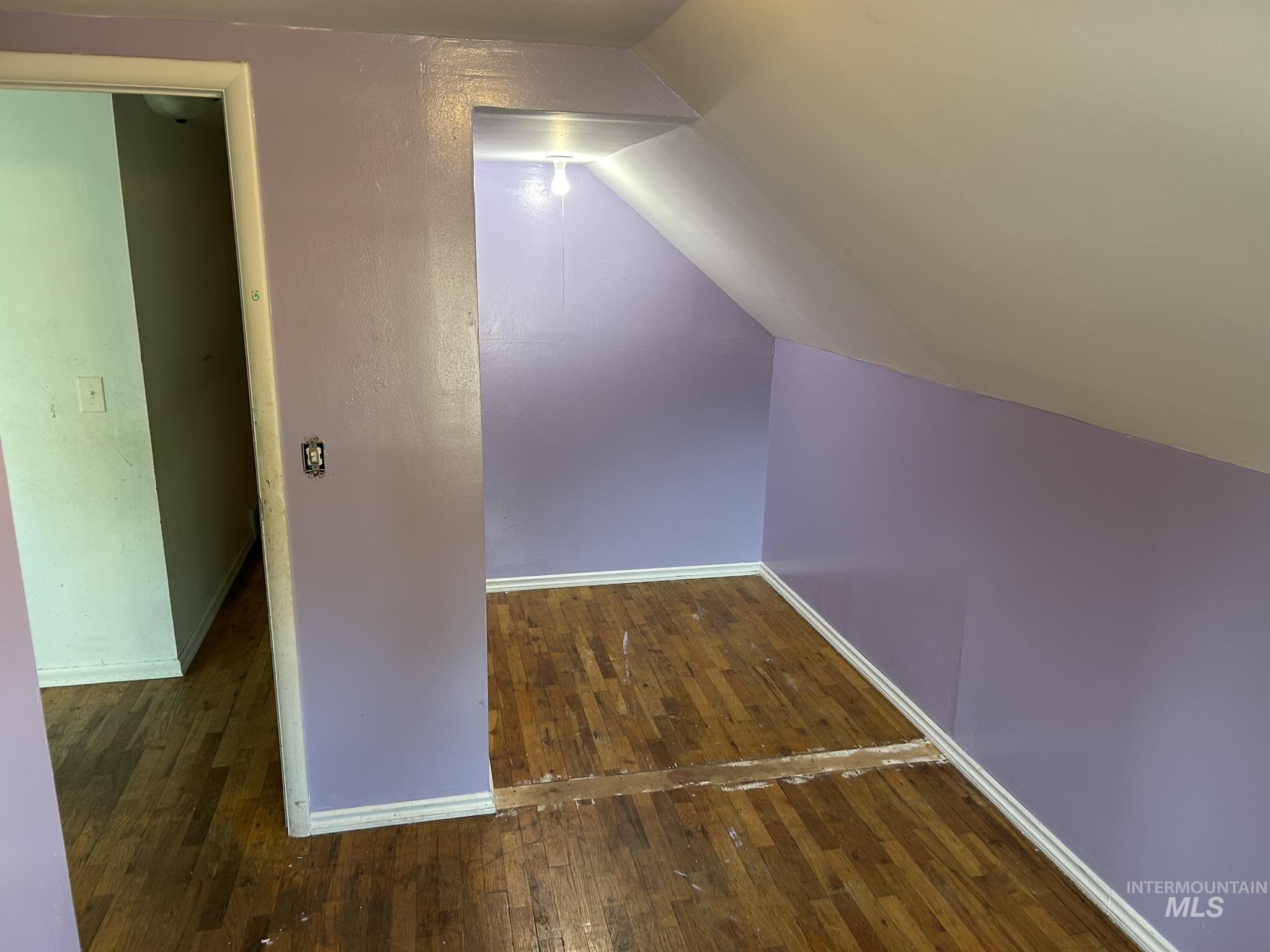 Additional living space with vaulted ceiling and dark wood-type flooring