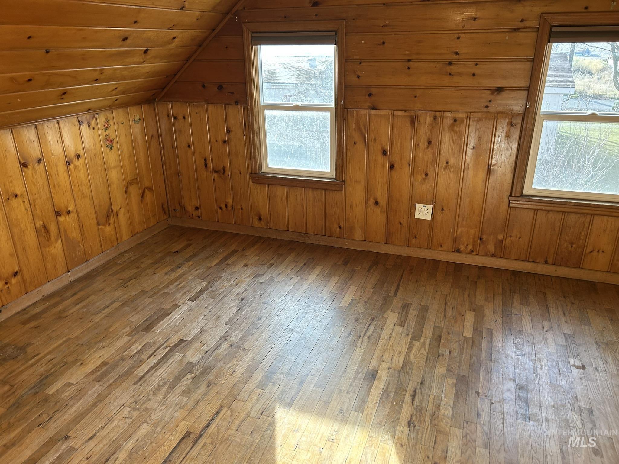 Bonus room with hardwood / wood-style floors, vaulted ceiling, and wooden walls