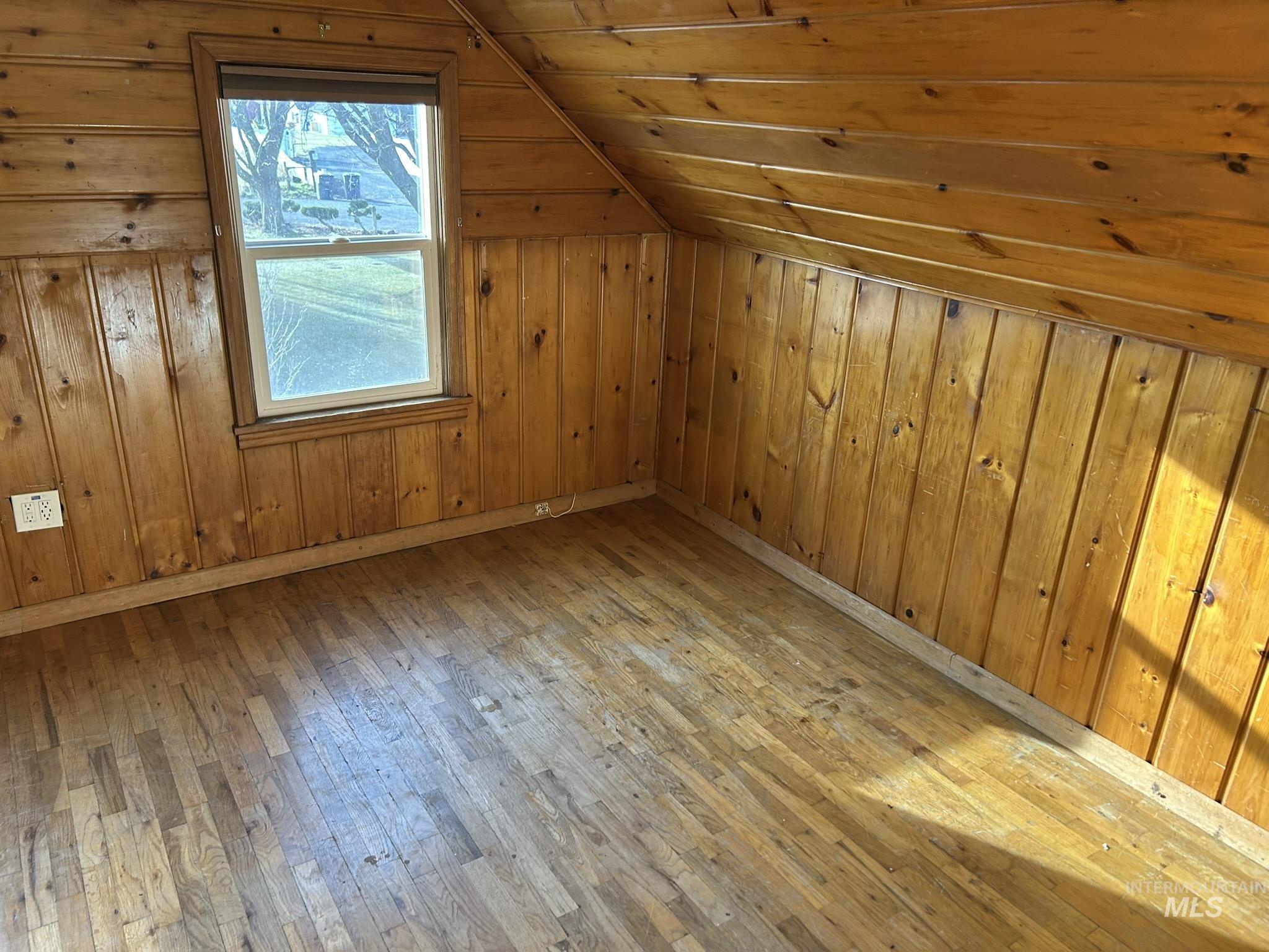 Additional living space with light wood-style floors, lofted ceiling, wood walls, and wooden ceiling