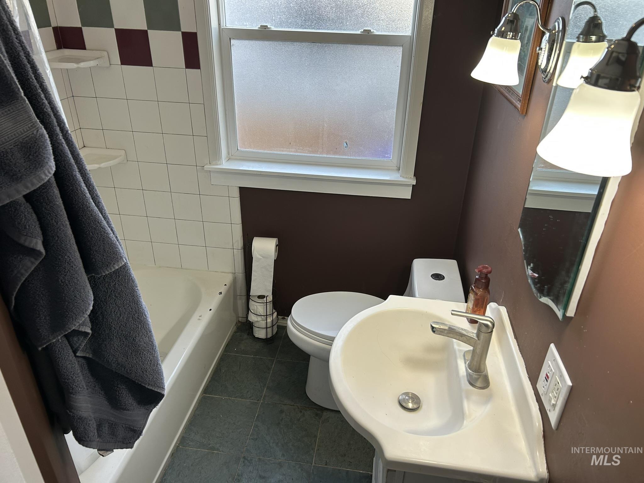 Bathroom with dark tile patterned flooring, a bath, and vanity