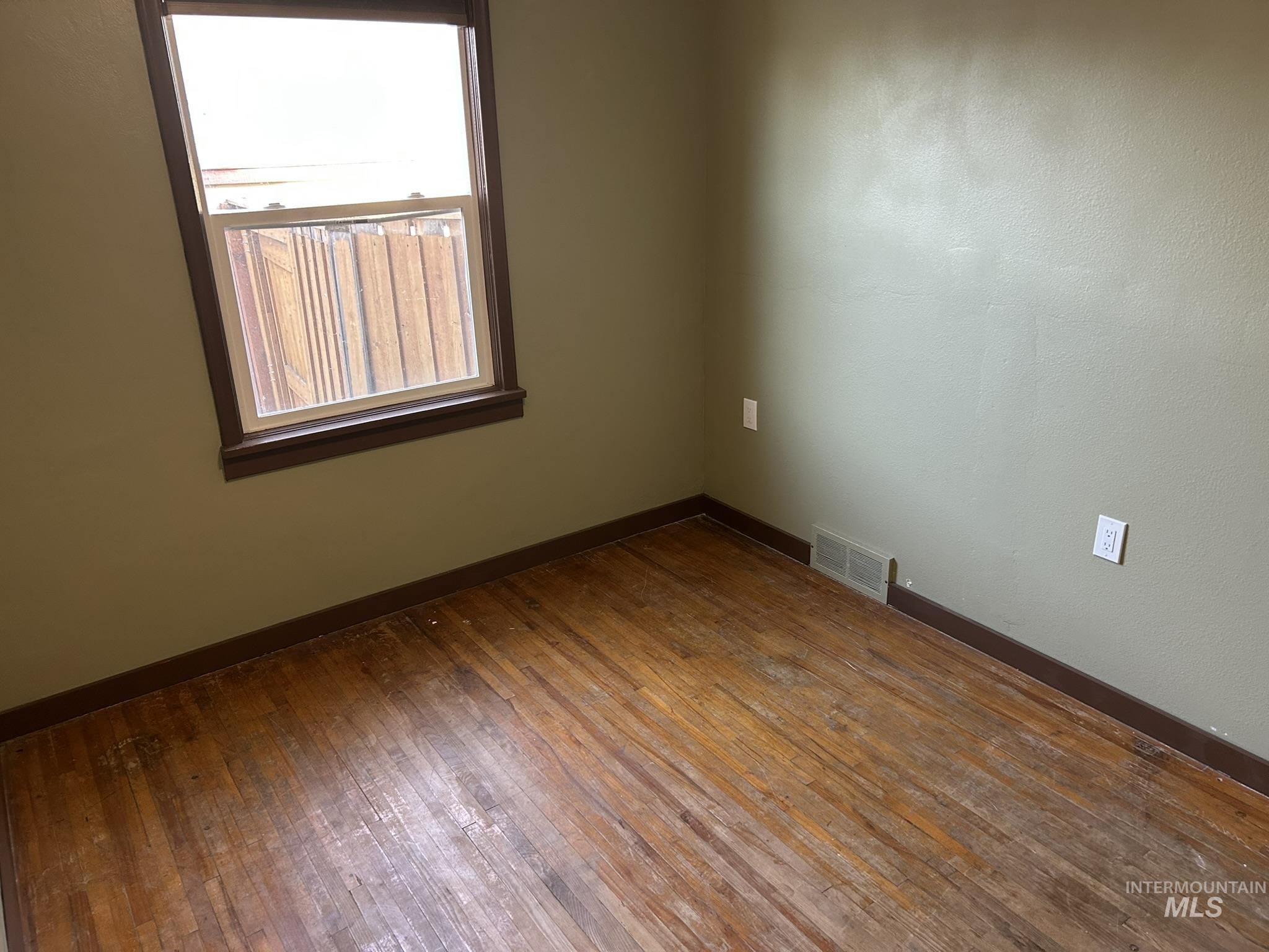 Unfurnished room with dark wood-type flooring and baseboards