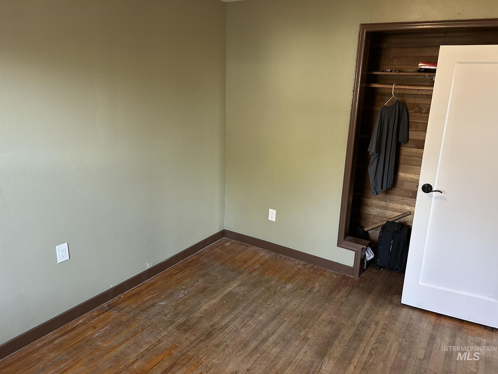 Unfurnished bedroom featuring dark wood-style flooring and a closet