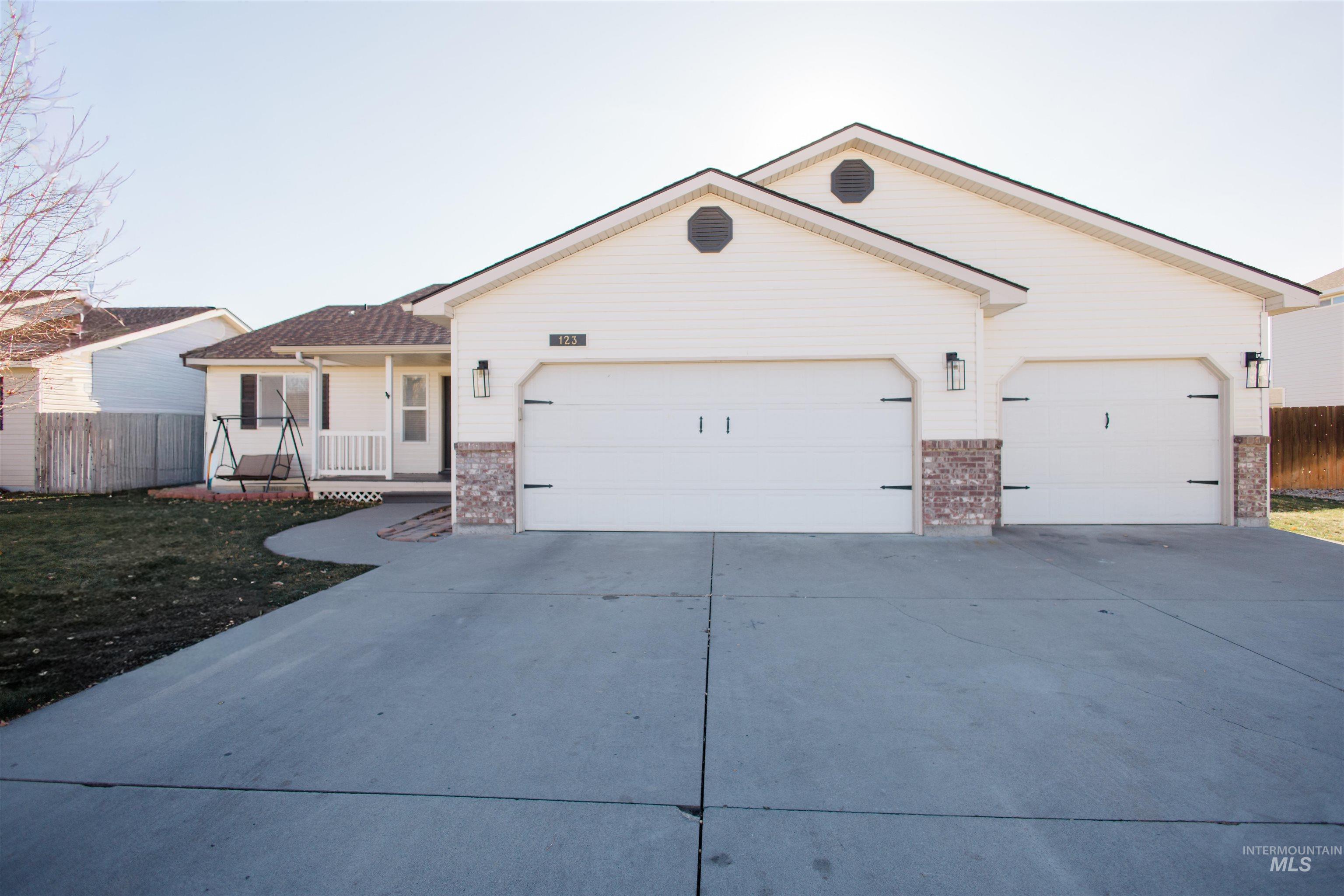 Single story home featuring driveway, brick siding, a garage, and a porch
