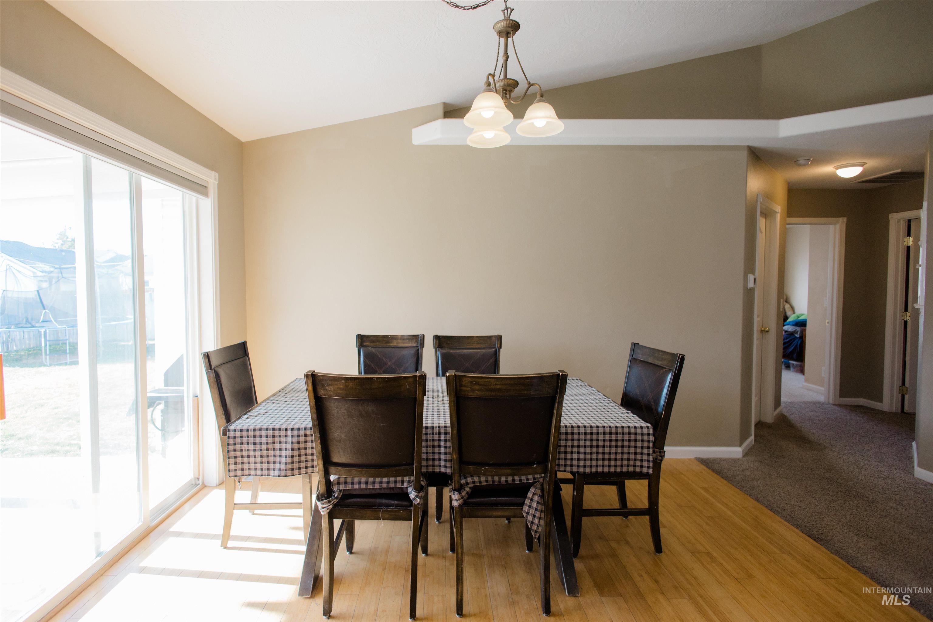 Dining room with lofted ceiling, wood finished floors, and a chandelier