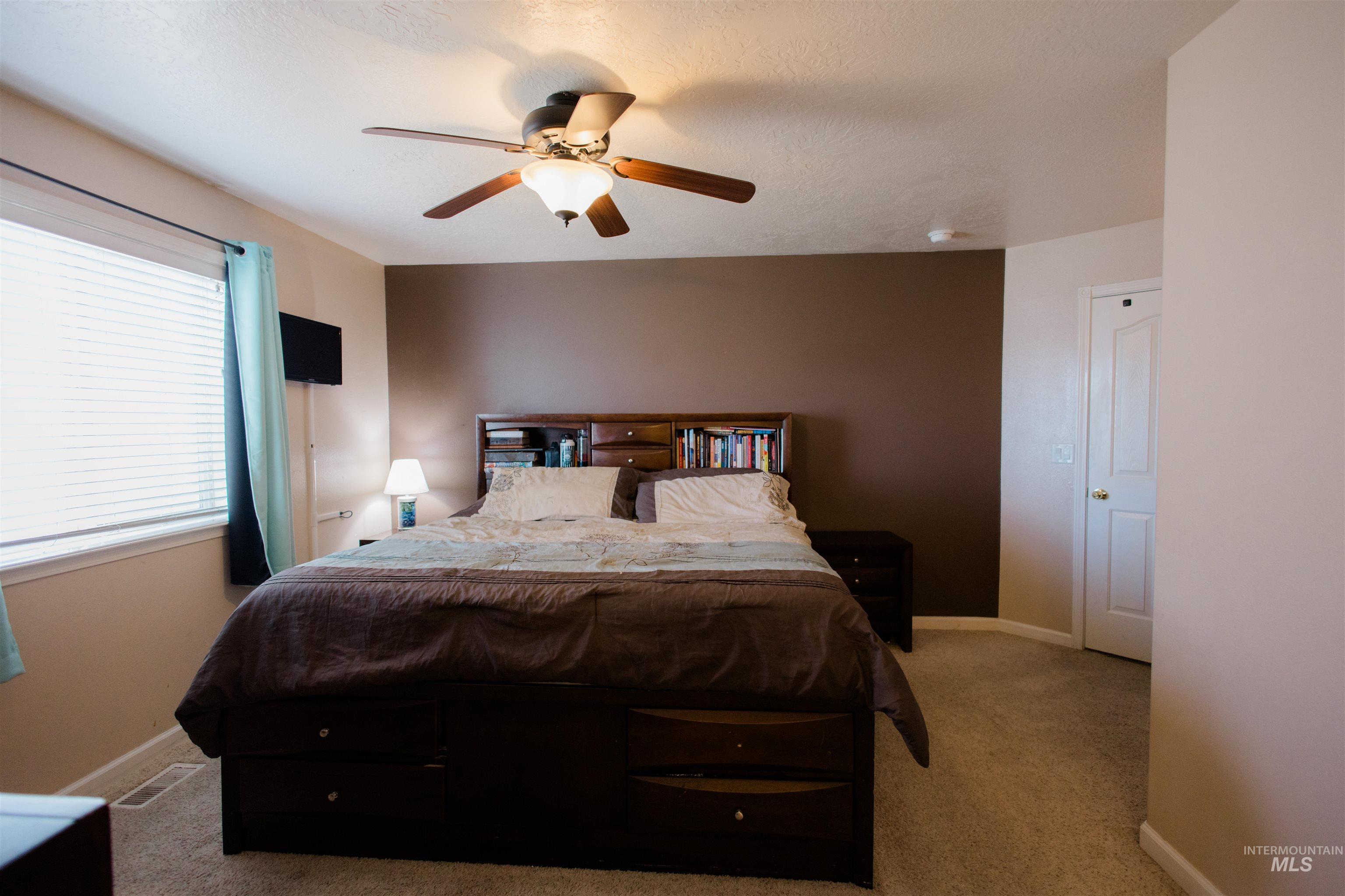 Carpeted bedroom with a ceiling fan and baseboards