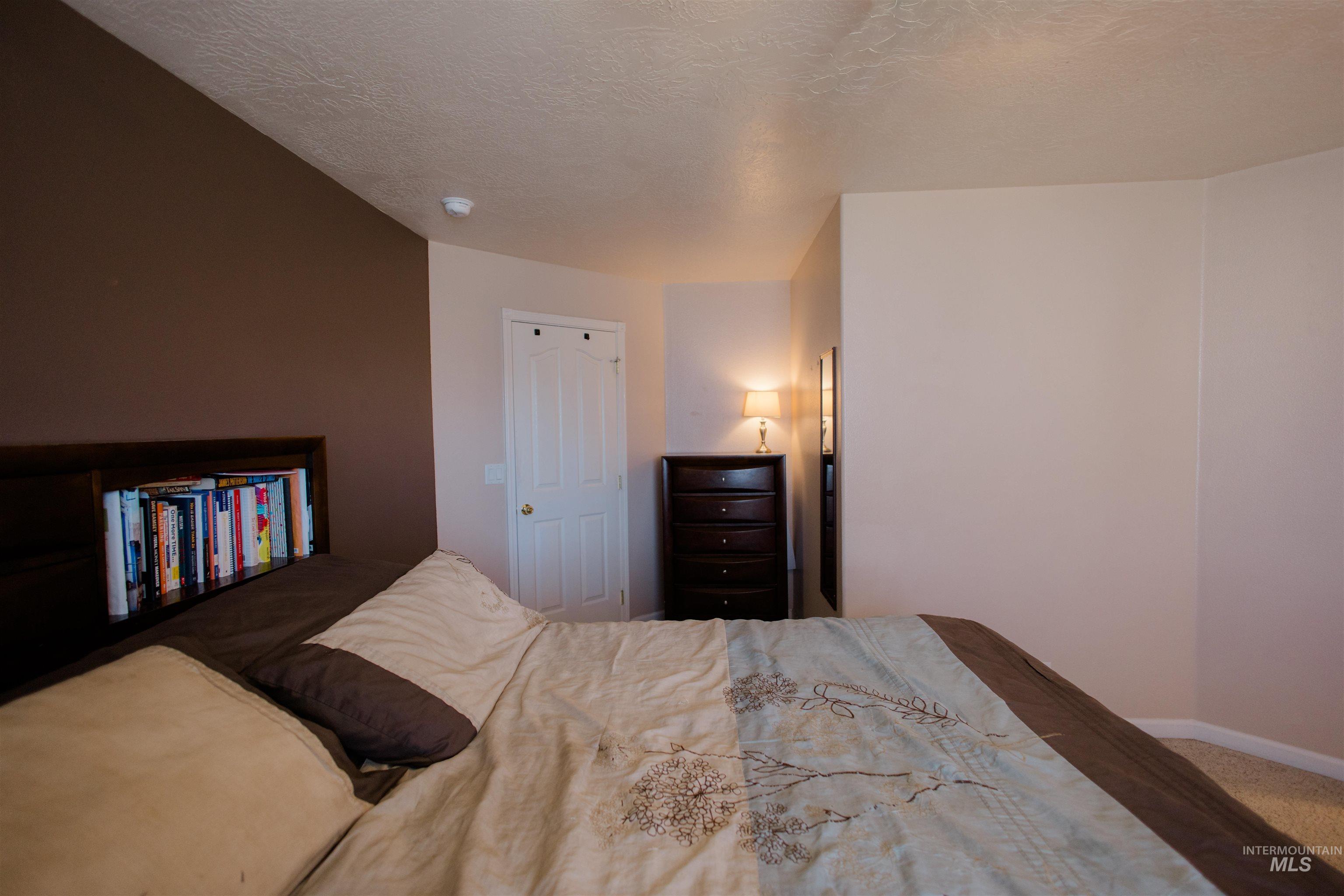 Carpeted bedroom with baseboards and a textured ceiling
