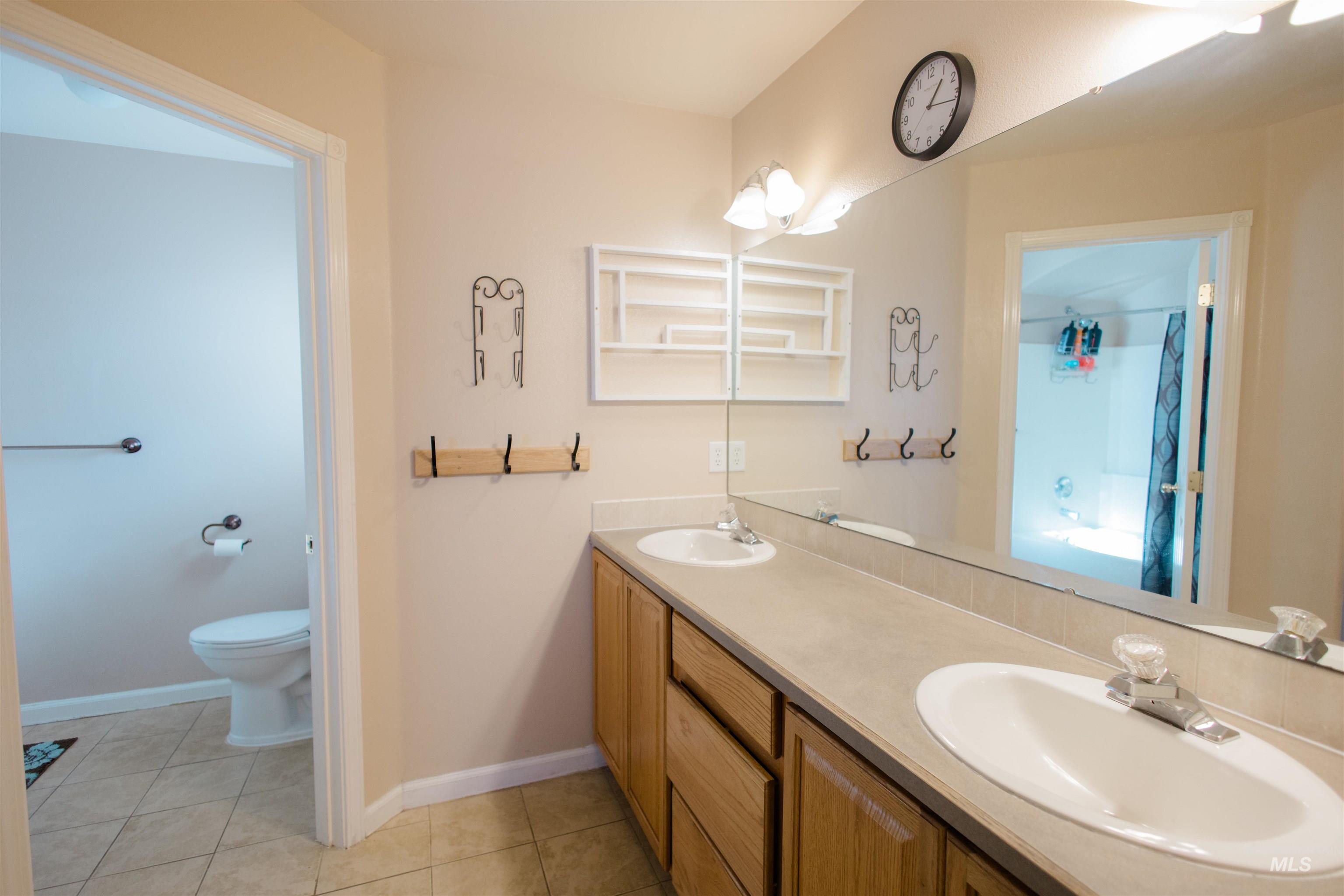 Full bathroom featuring double vanity, light tile patterned floors, a shower, and a tub to relax in