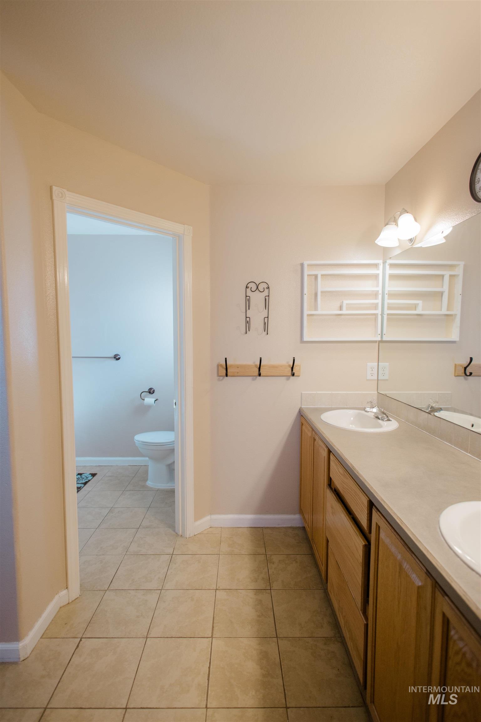 Full bath featuring double vanity and light tile patterned floors