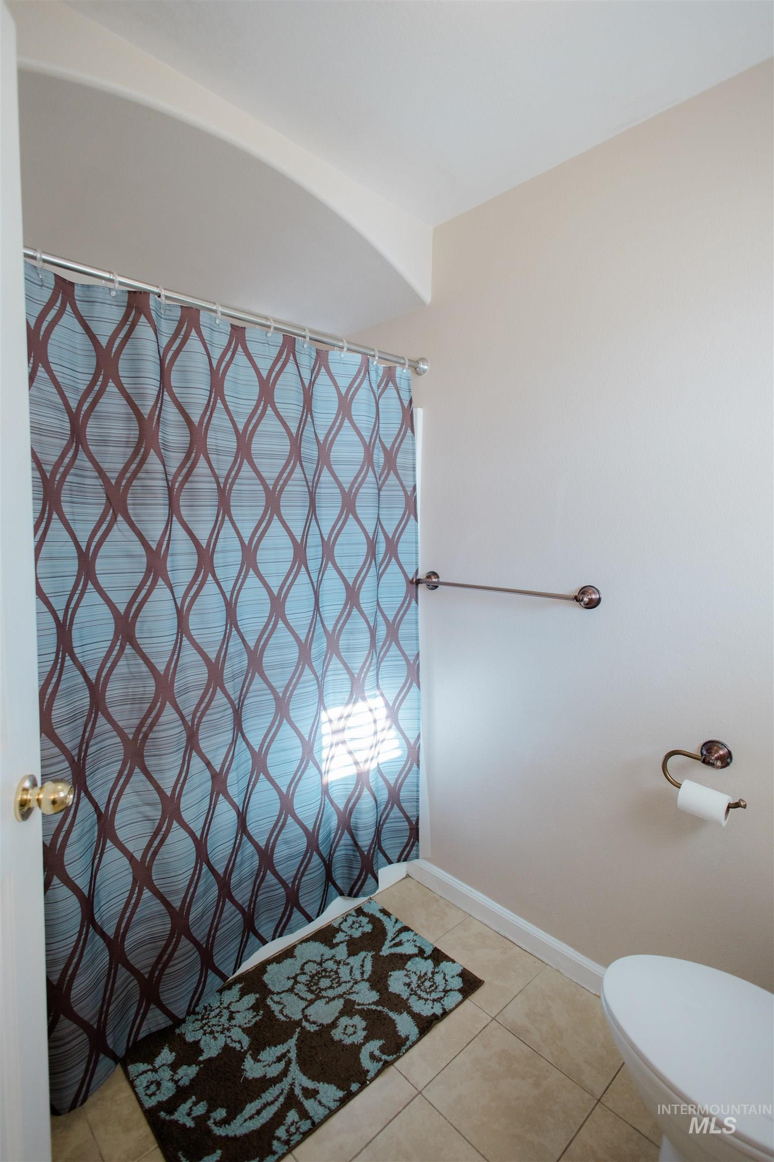 Bathroom featuring curtained shower and light tile patterned floors