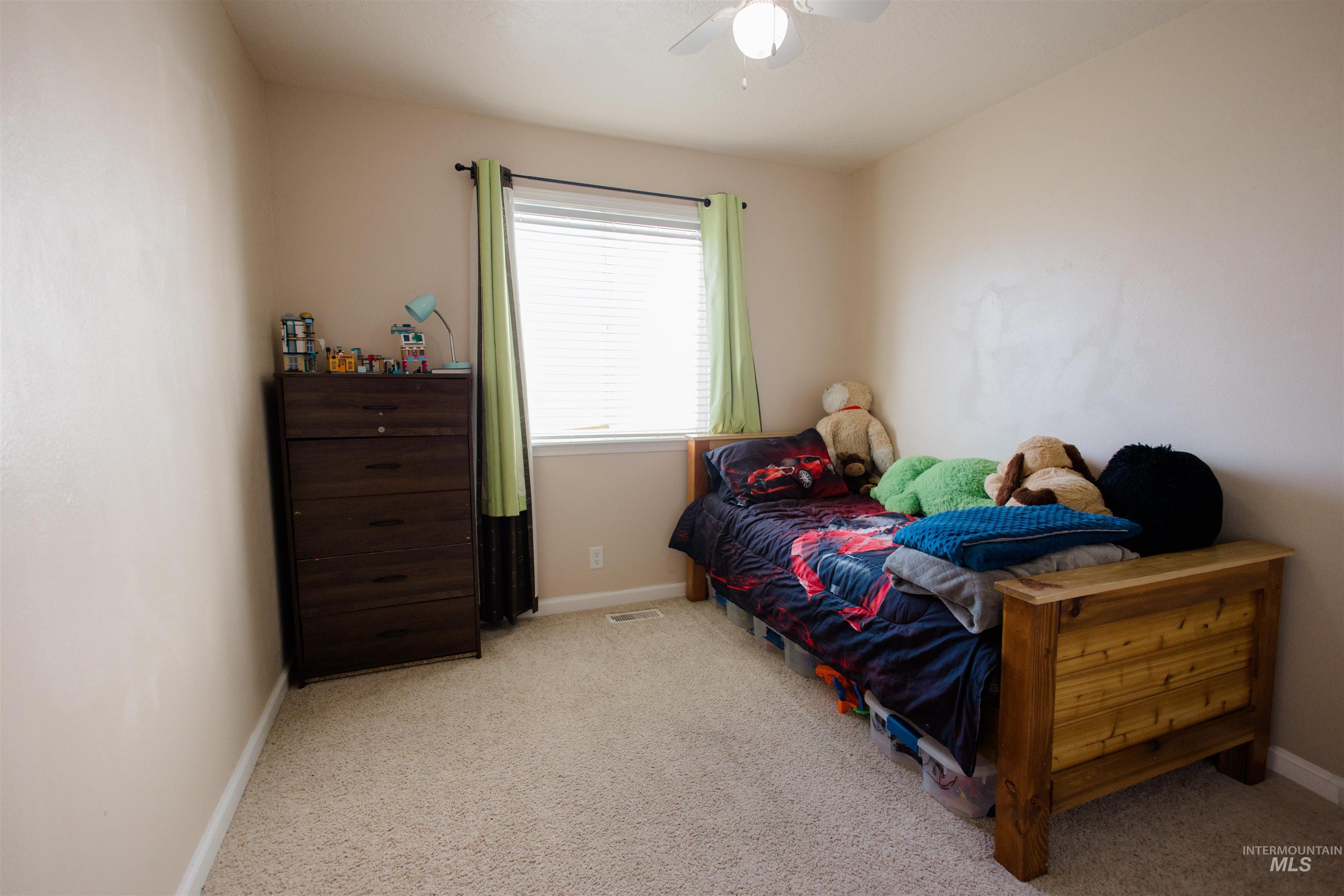 Bedroom with light colored carpet and a ceiling fan