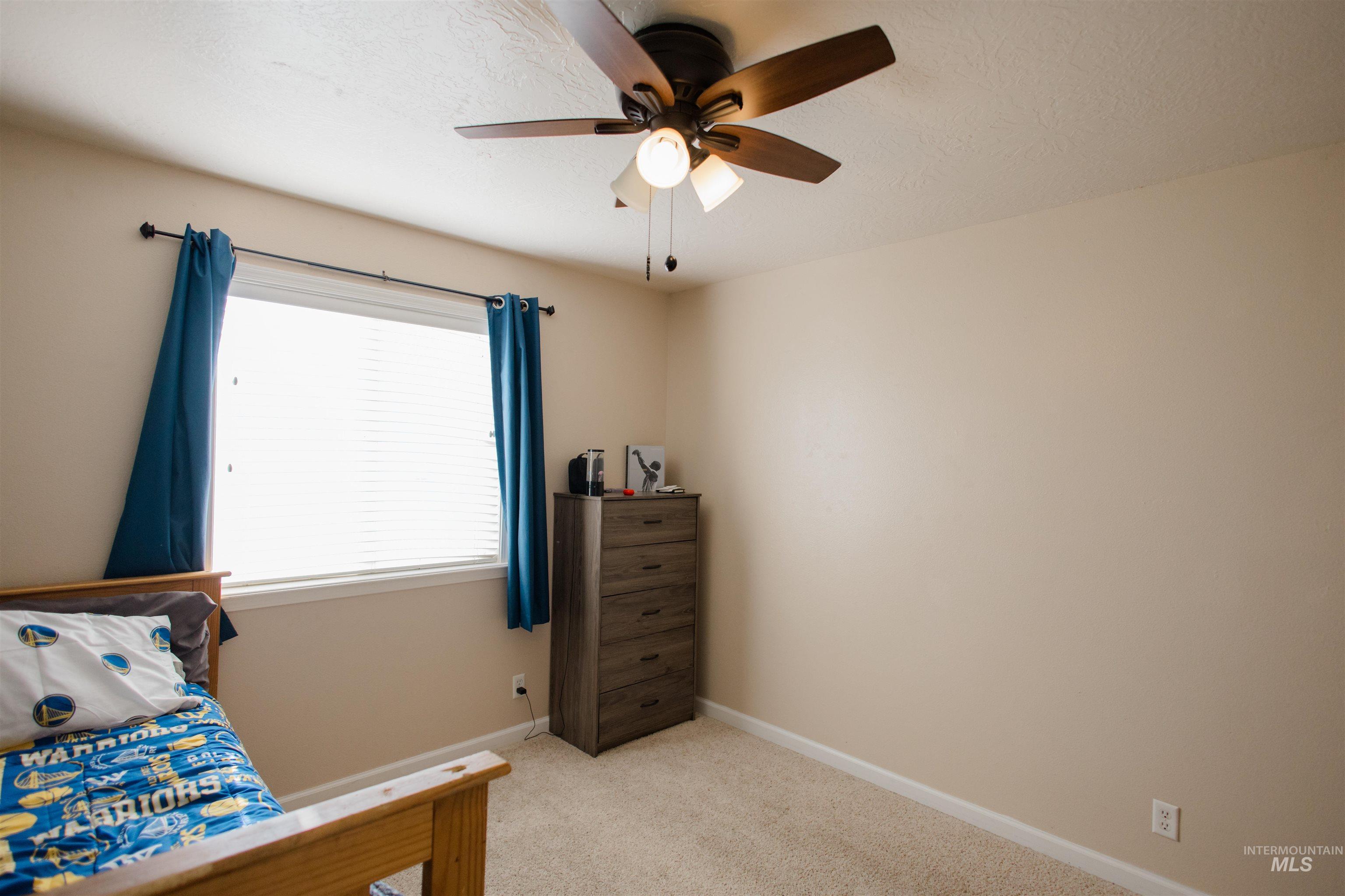 Bedroom featuring light carpet, a ceiling fan, and a textured ceiling