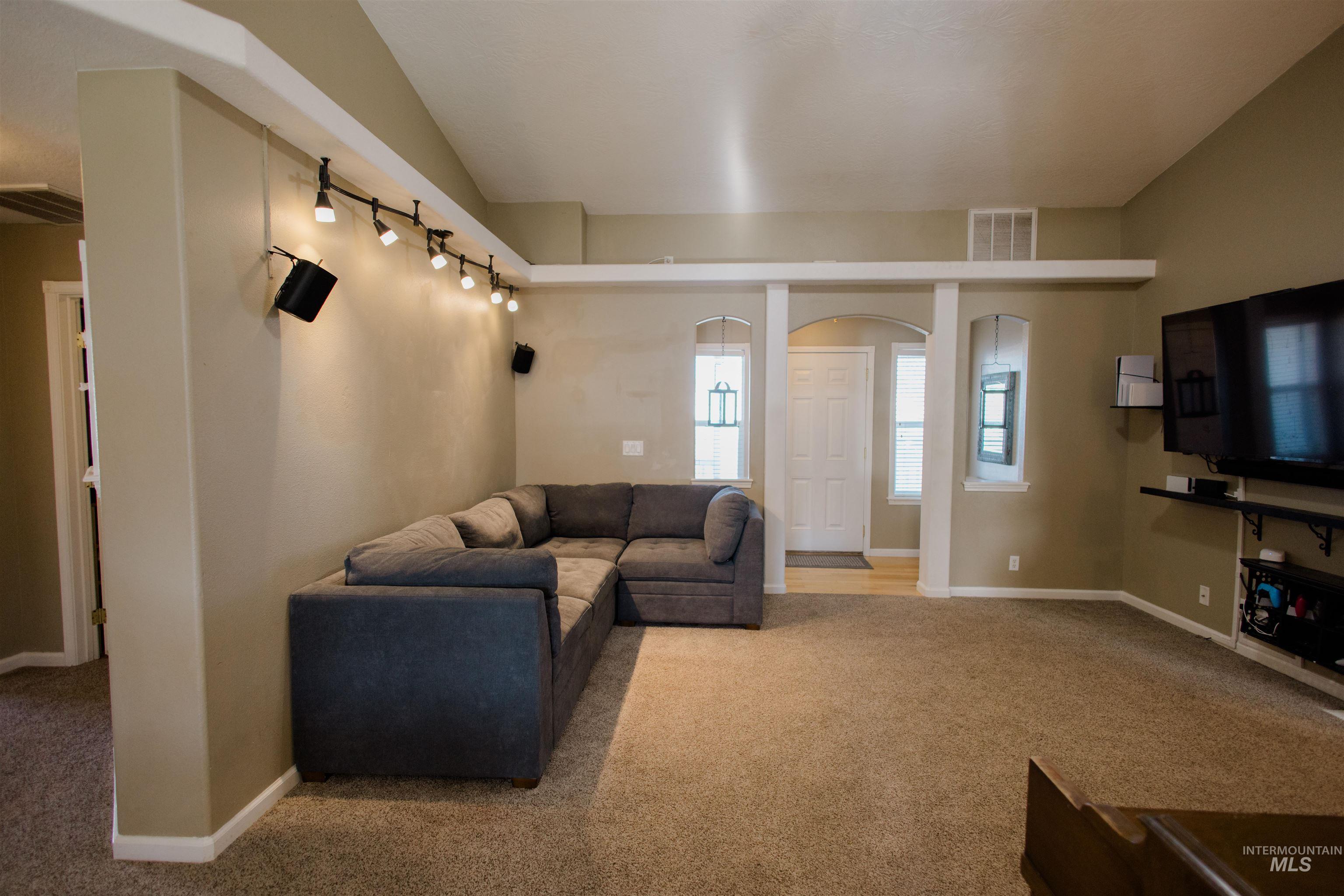 Living area with light colored carpet and arched walkways