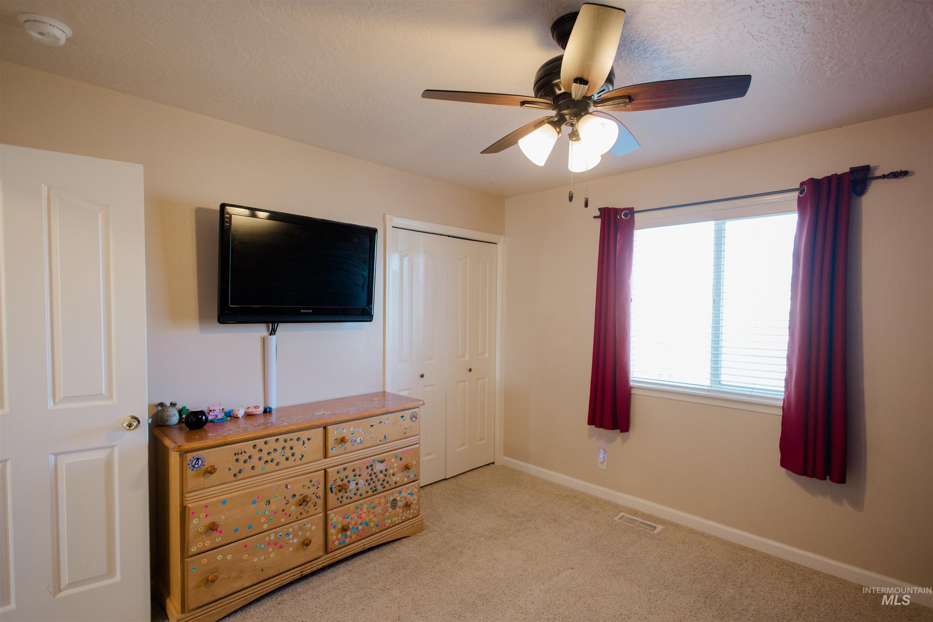 Bedroom featuring light carpet, ceiling fan, a textured ceiling, and a closet