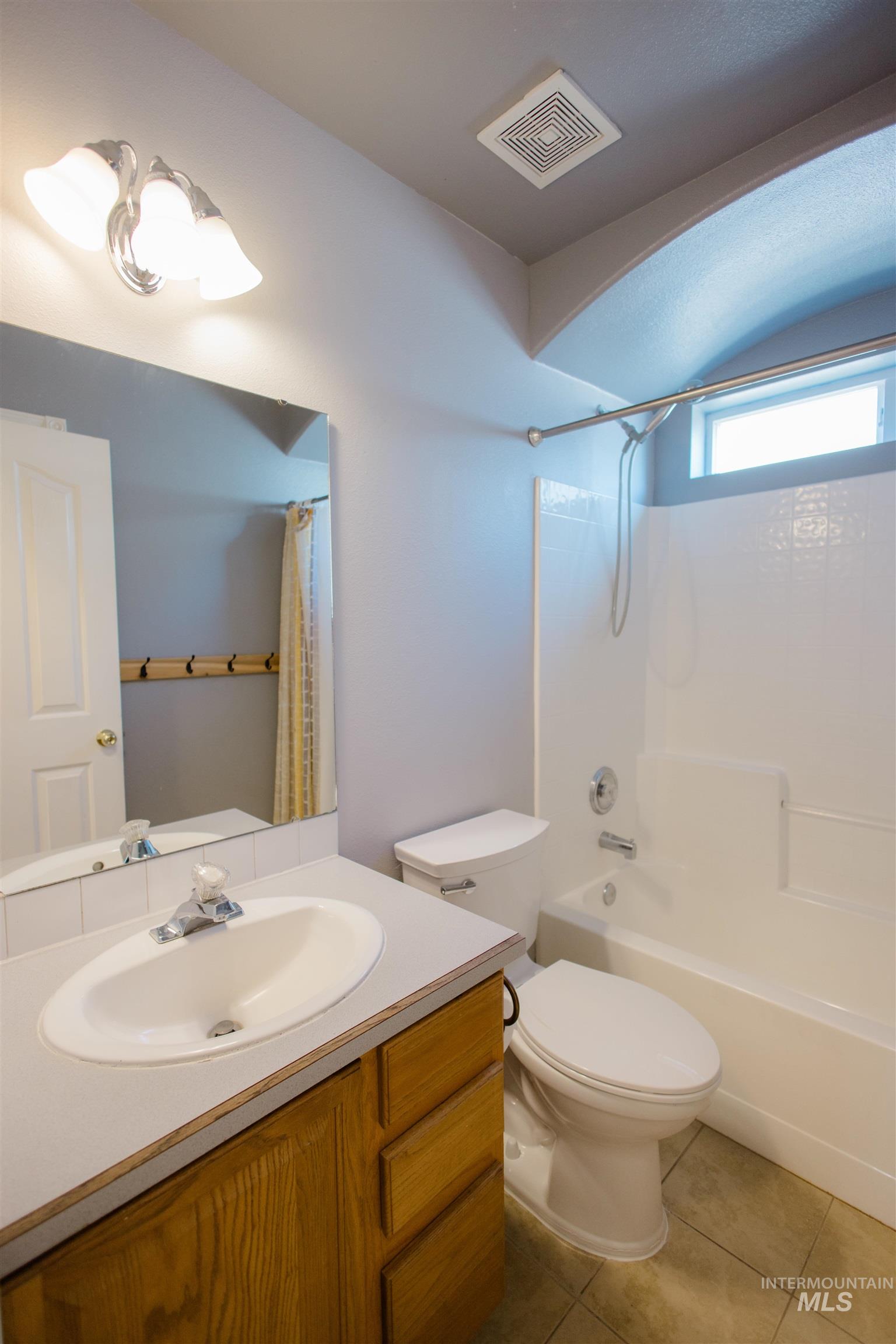 Bathroom featuring vanity, shower / bath combination with curtain, and light tile patterned floors