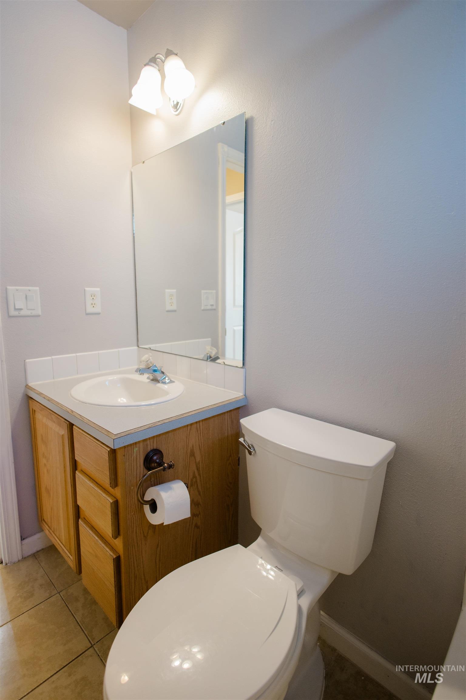 Half bathroom featuring vanity and light tile patterned floors