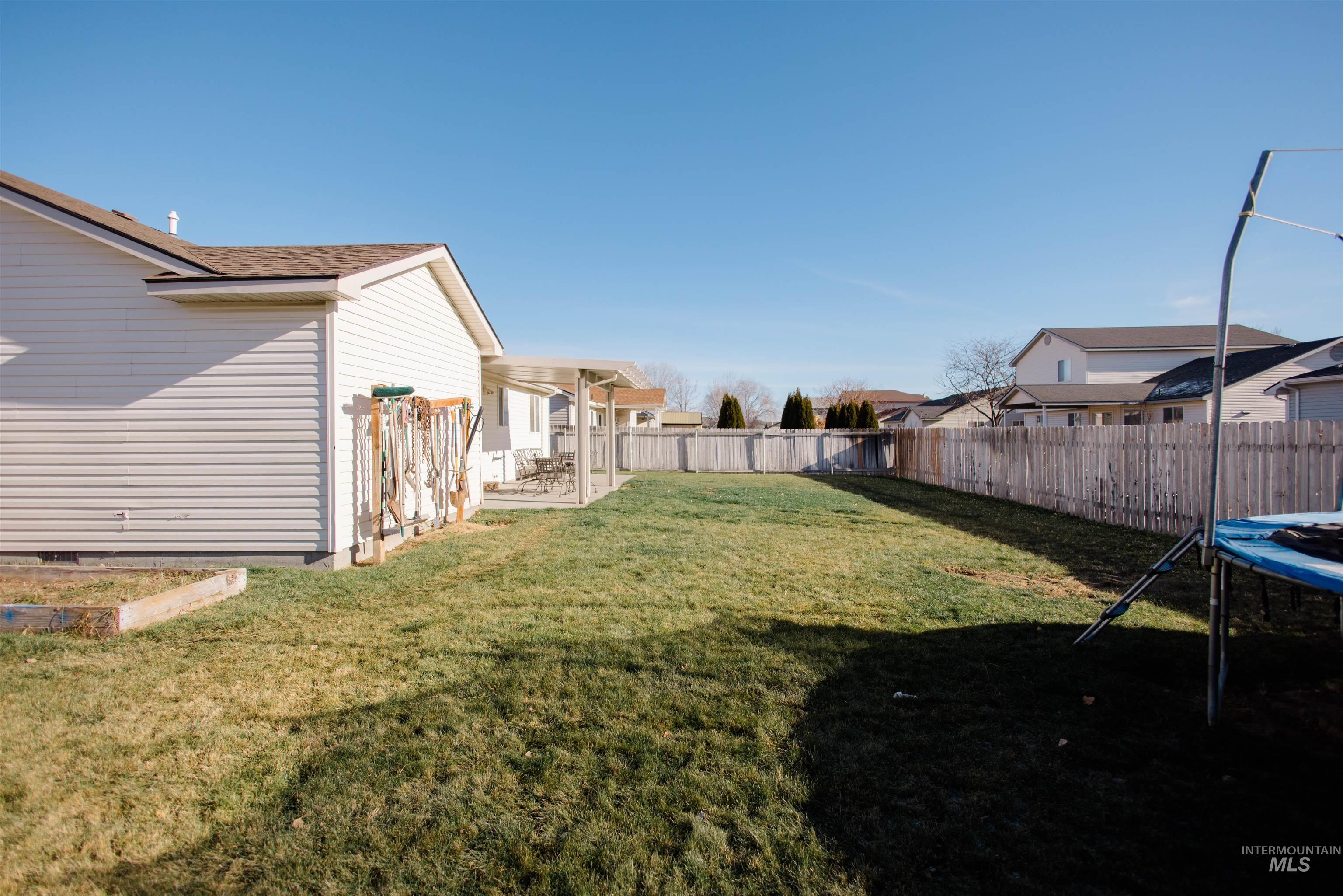 Fenced backyard with a patio area and a trampoline