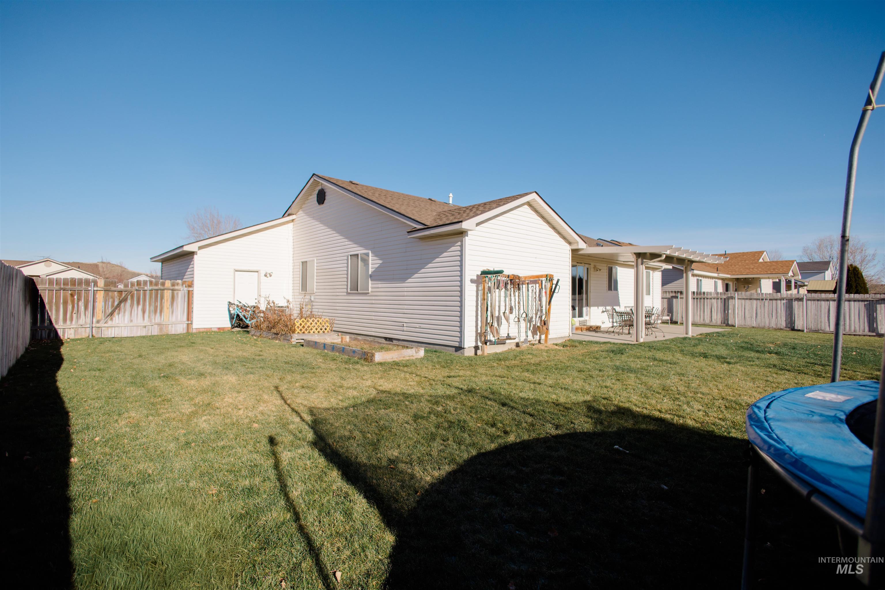 Rear view of property featuring a fenced backyard, a patio, a trampoline, and a pergola