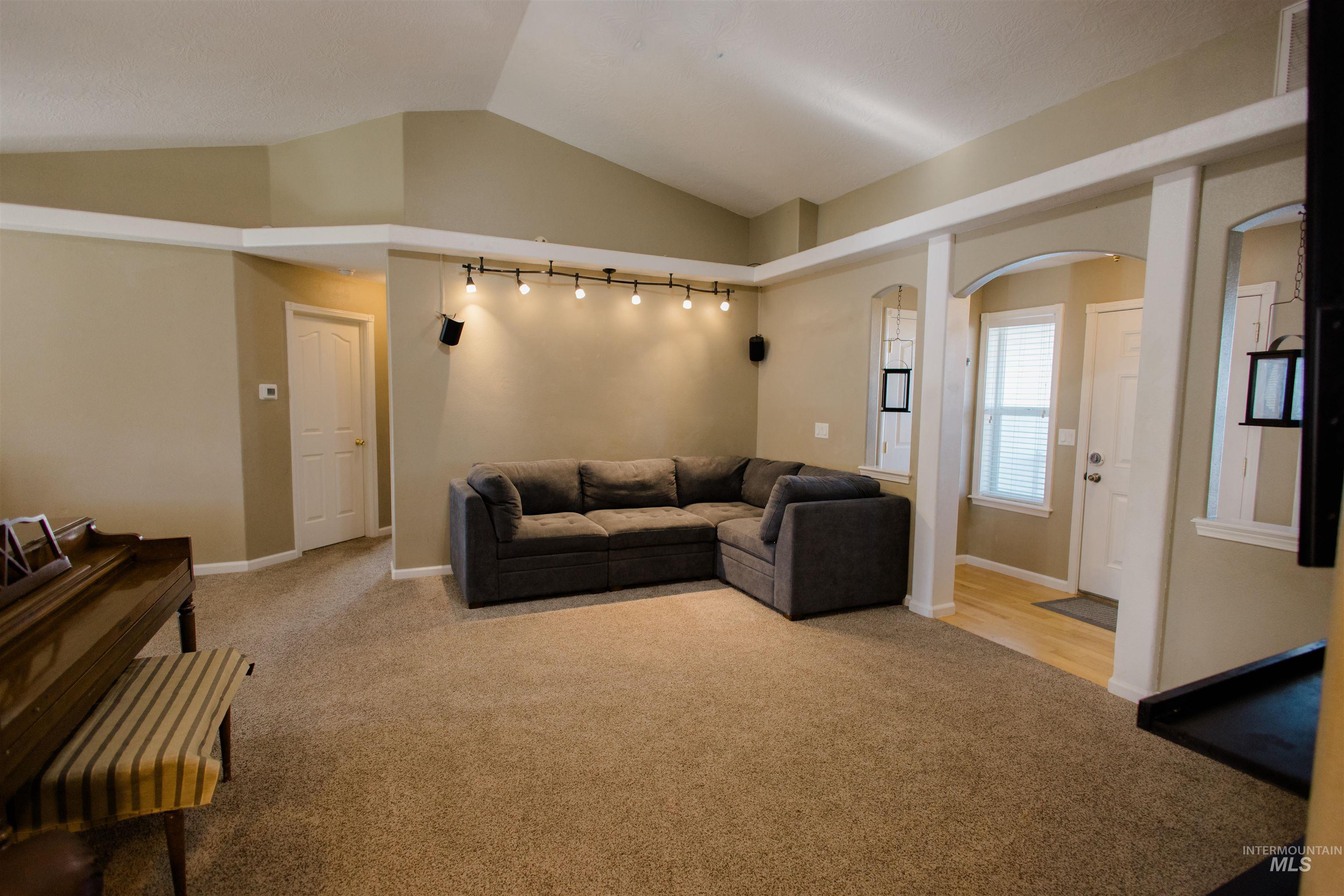 Living area featuring lofted ceiling, light carpet, and arched walkways