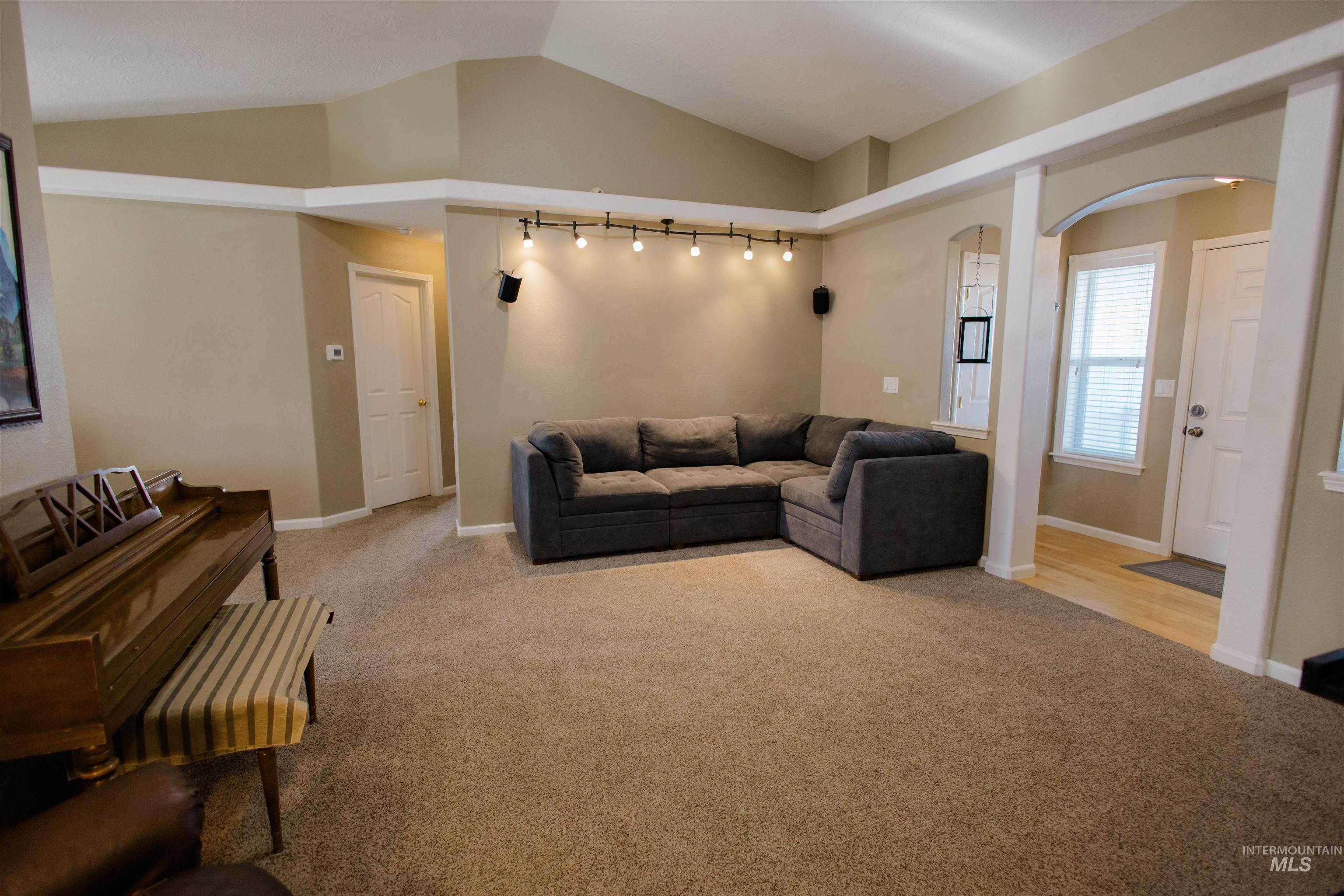 Living room with lofted ceiling, light colored carpet, and arched walkways