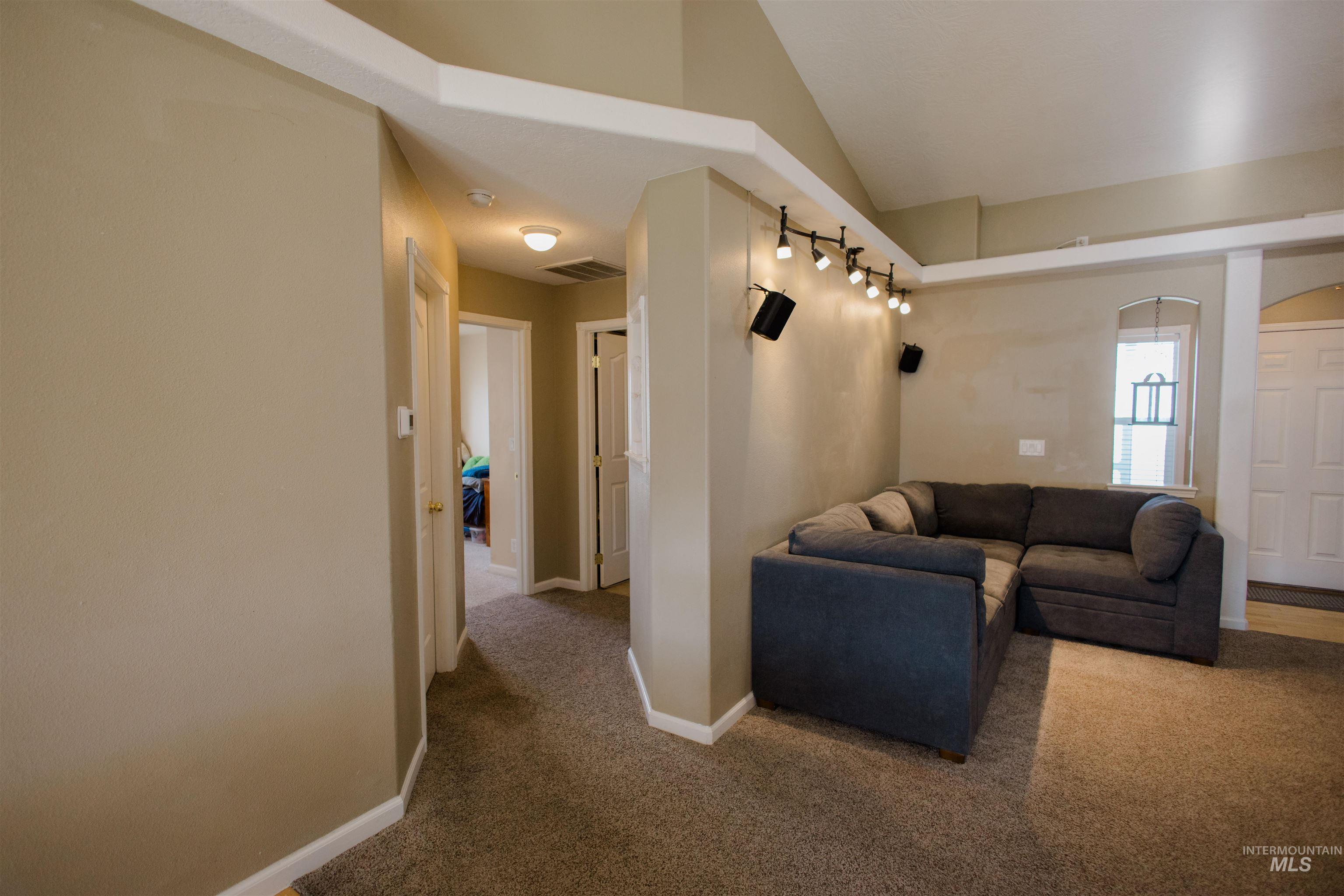 Carpeted living area with baseboards and vaulted ceiling