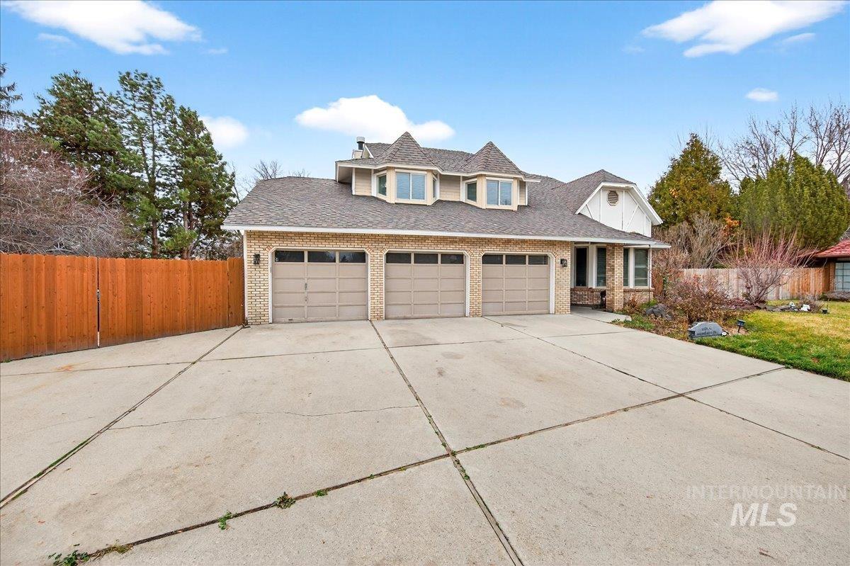 Traditional-style home featuring concrete driveway, a shingled roof, an attached garage, and brick siding