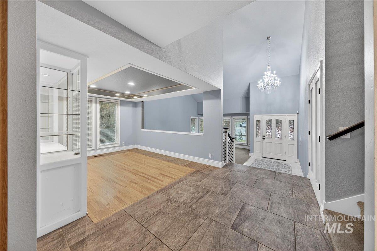 Entrance foyer featuring a chandelier, stairway, a textured wall, and tile patterned floors