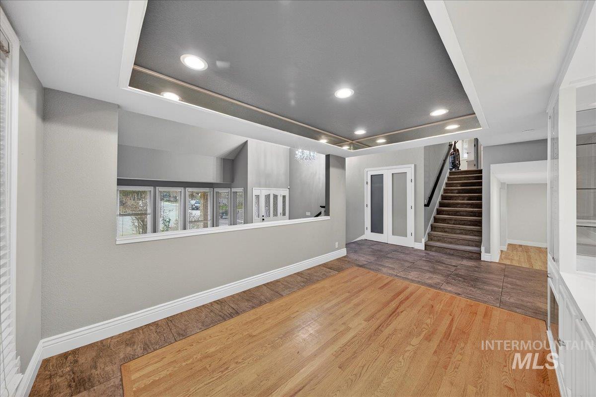 Spare room with wood-type flooring, a tray ceiling, recessed lighting, and stairs