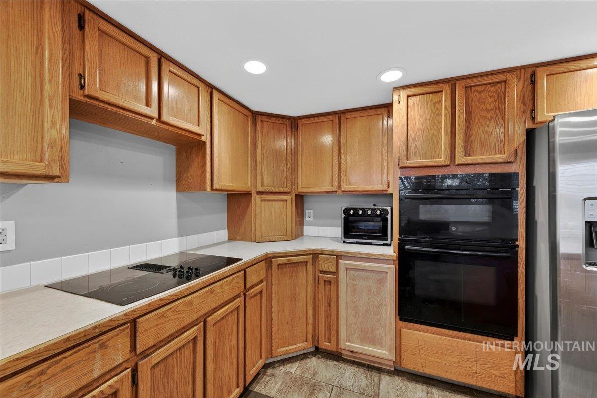 Kitchen with light countertops, black appliances, brown cabinets, and recessed lighting