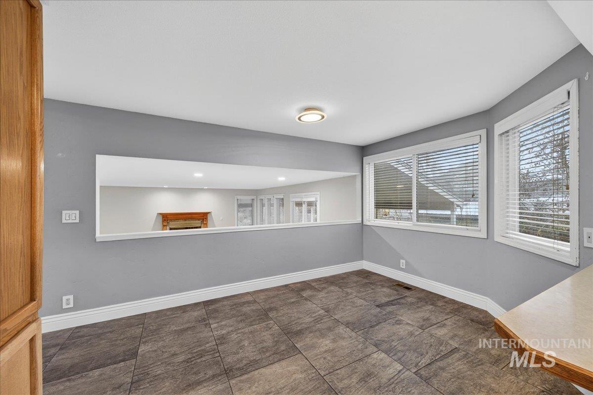 Unfurnished room featuring a fireplace and baseboards