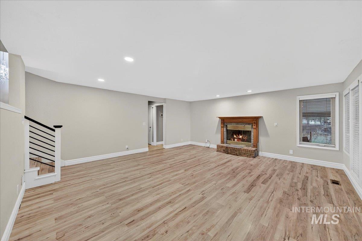 Unfurnished living room with light wood-style flooring, recessed lighting, stairs, and a fireplace