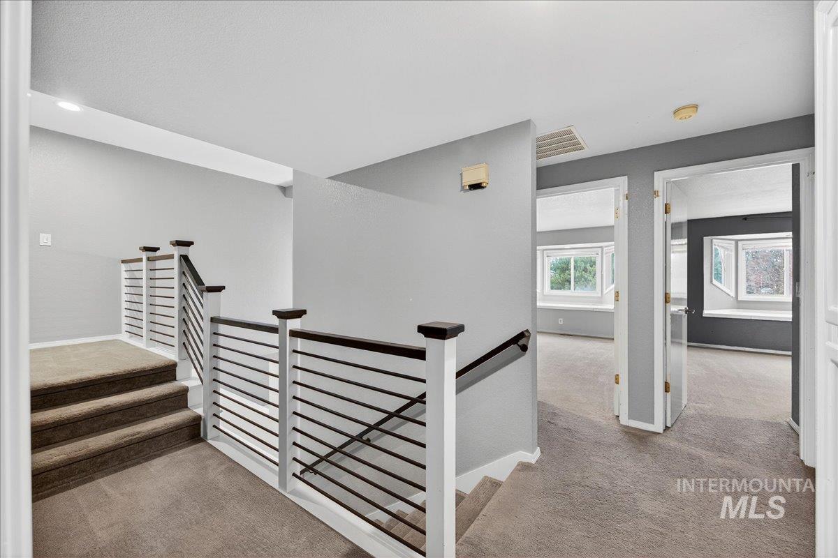 Hall with light colored carpet, an upstairs landing, and stairs
