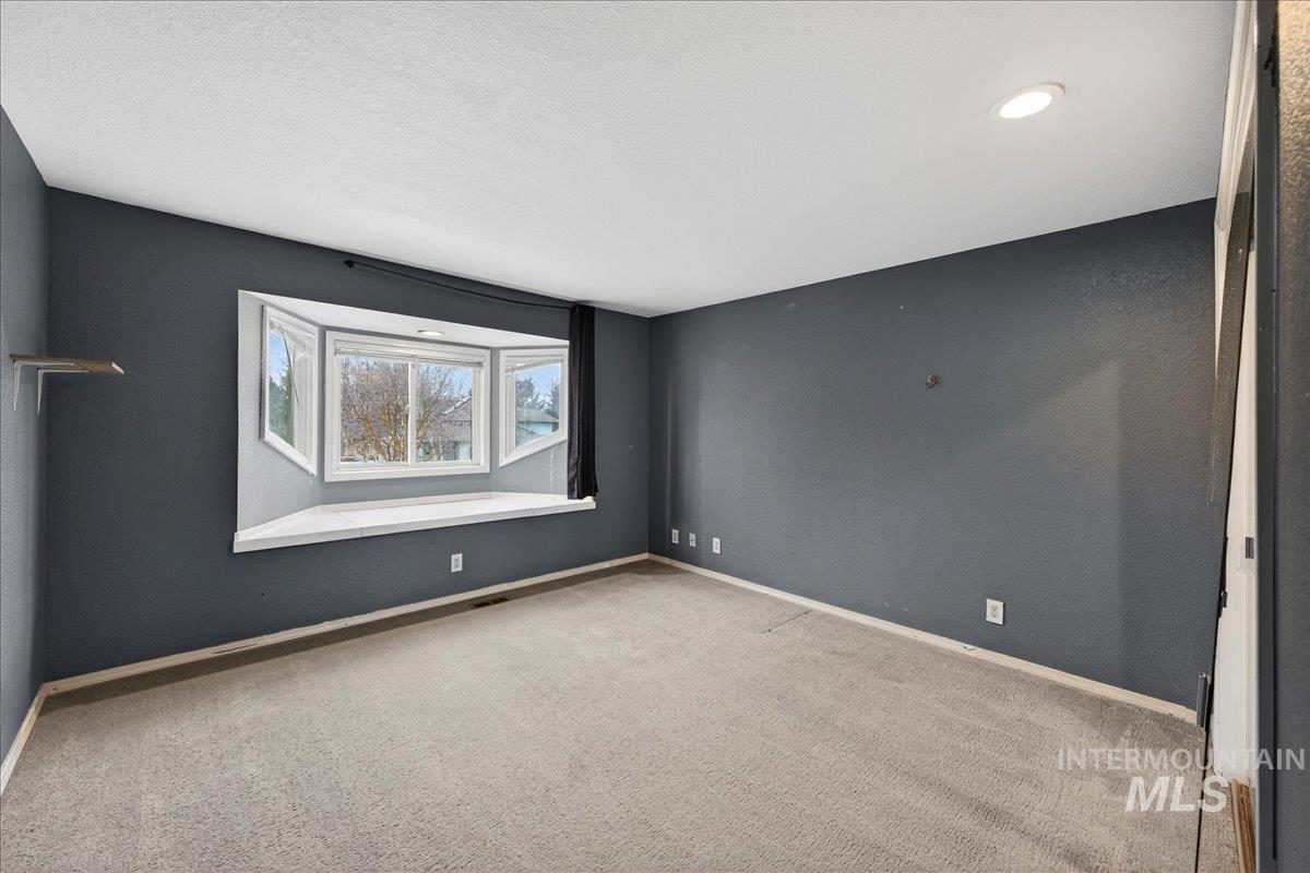 Carpeted empty room featuring baseboards and a textured ceiling
