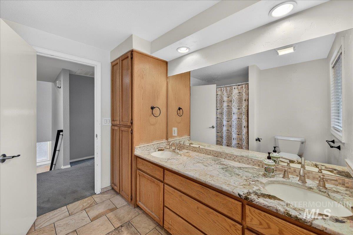 Full bath with double vanity and a shower with shower curtain