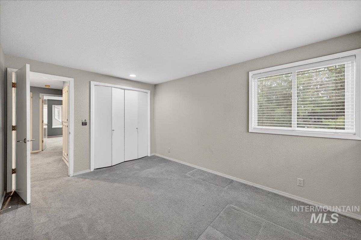 Unfurnished bedroom with carpet, a closet, a textured wall, and a textured ceiling