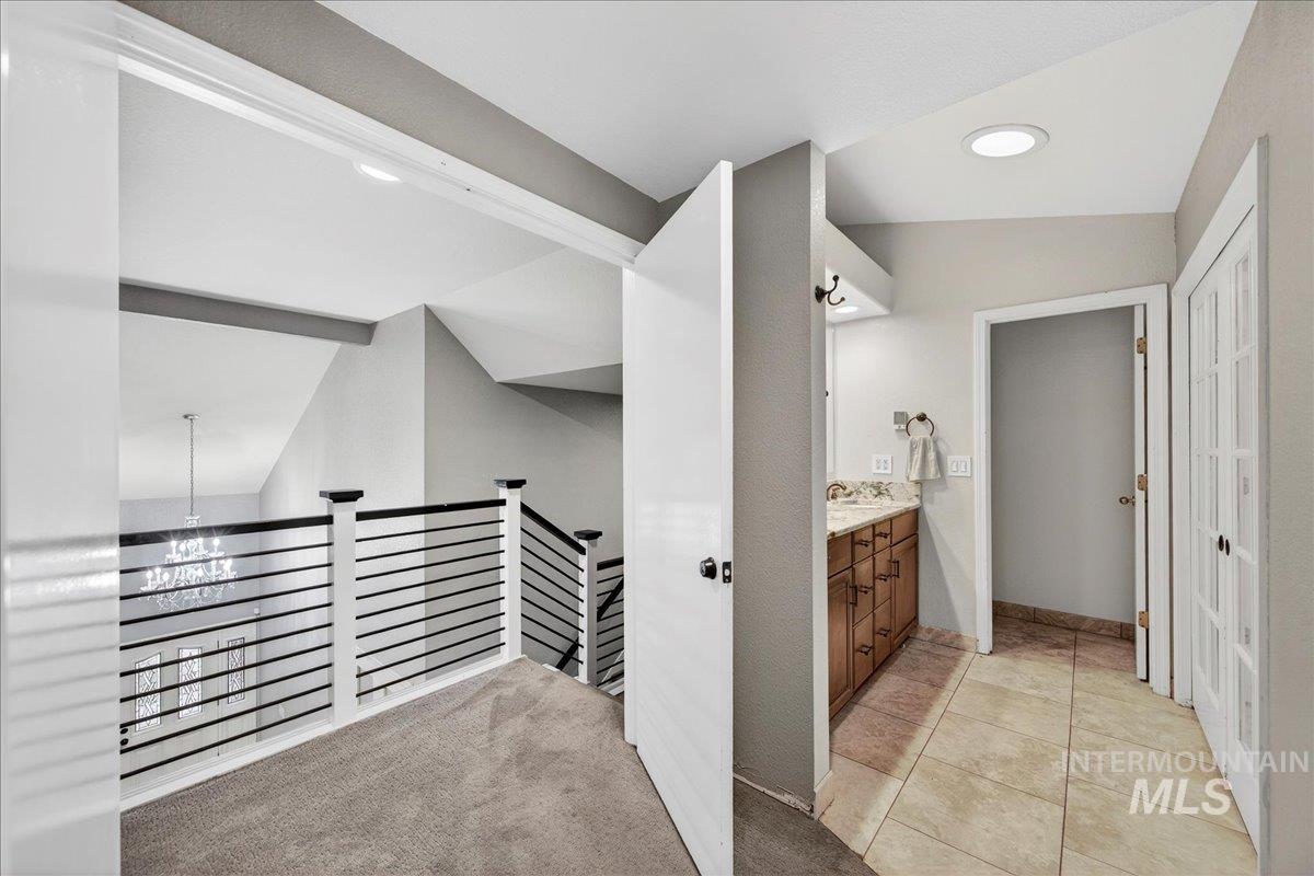 Hall featuring light colored carpet, an upstairs landing, lofted ceiling, recessed lighting, and light tile patterned floors