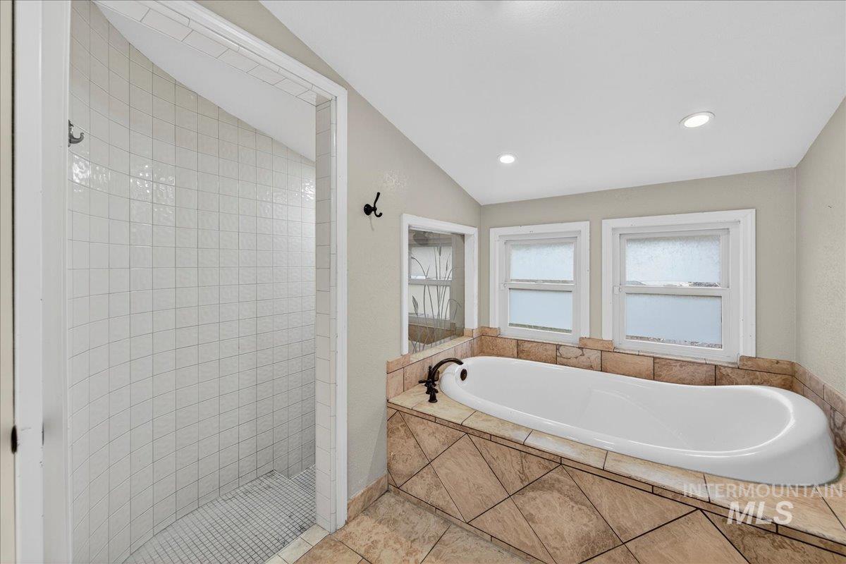 Full bath with a garden tub, a walk in shower, lofted ceiling, and recessed lighting